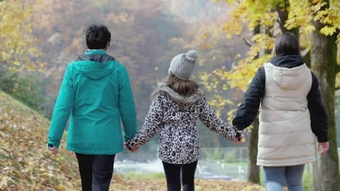 View from the back, two granddaughter on a walk with their grandmother holding Stock Footage 229652156