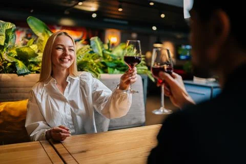 View from back of unrecognizable elegant man clinking glasses of red wine with Stock Photos