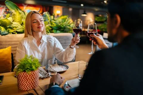 View from back of unrecognizable man in suit clinking glasses of red wine with Stock Photos