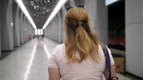 A view from the back of a woman with a backpack walking along a metro station. Stock Footage 313472074
