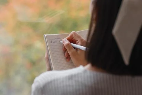 View from back, woman writes notes in notebook or diary. mental health care Stock Photos