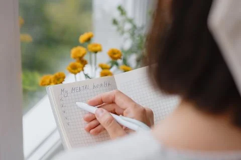 View from back, woman writes notes in notebook or diary. mental health care Stock Photos