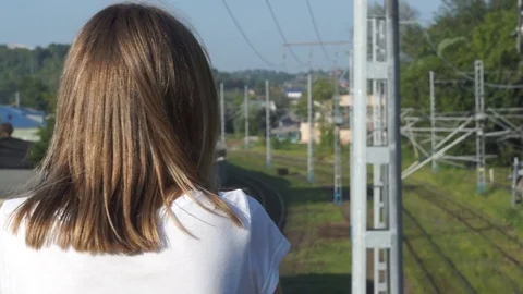 View from the back to a young girl looking at the railway tracks and rails Stock Footage 78123388