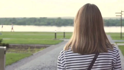 The view from the back to a young girl with medium length hair strolling alone Stock Footage 77576285