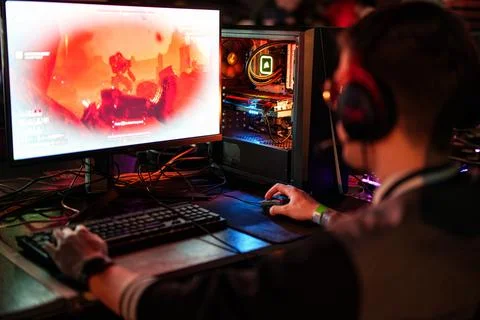 View from the back of young man playing video game on desktop PC computer Stock Photos