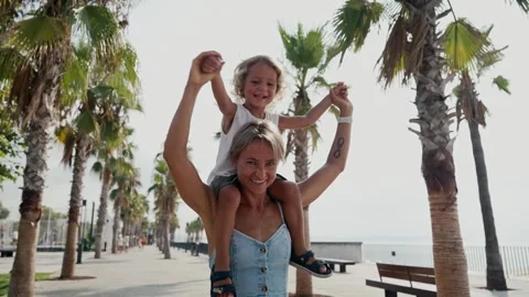 View back young mother with his little son sitting on parent shoulders in field Stock Footage 247563710