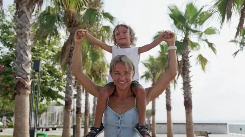 View back young mother with his little son sitting on parent shoulders in field Stock Footage 247563736