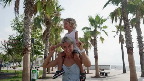 View back young mother with his little son sitting on parent shoulders in field Stock Footage 248183668