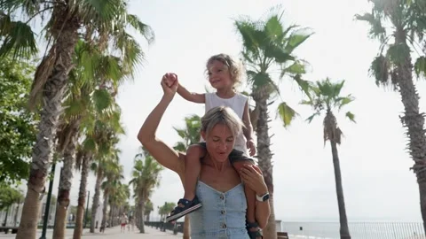 View back young mother with his little son sitting on parent shoulders in field Stock Footage 248183677