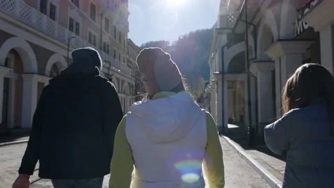 View from the back.Three tourists are walking along a beautiful street in Europe Stock Footage 165622588