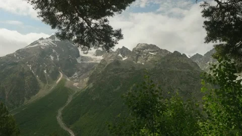 View of bare mountains with peaks covered with snow and with white fluffy clouds Stock Footage 138743156