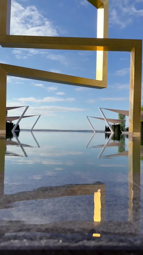 View From Base of Angular Golden Art Object Toward Endless Public Pool Horizon Stock Footage 282534279