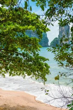 View of the beach and mountains through the foliage of trees Stock Photos