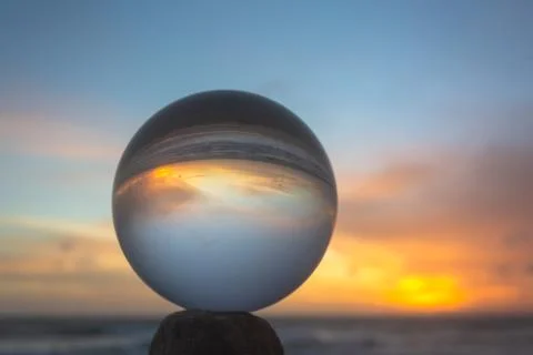 View of the beach in beautiful sunset inside crystal ball. Stock Photos