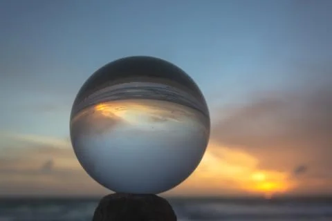 View of the beach in beautiful sunset inside crystal ball. Stock Photos