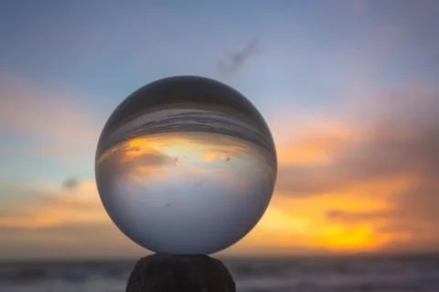 View of the beach in beautiful sunset inside crystal ball. Stock Photos
