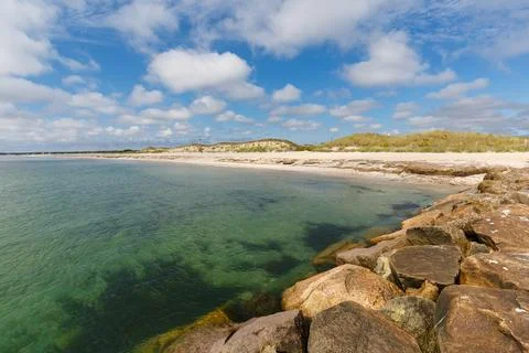 View of beach with clear waters and sand dunes while standing on rock jetty Stock Photos