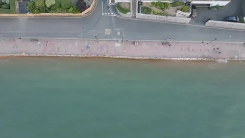 A view of a beach with a green ocean and a sidewalk Stock Footage 297950110