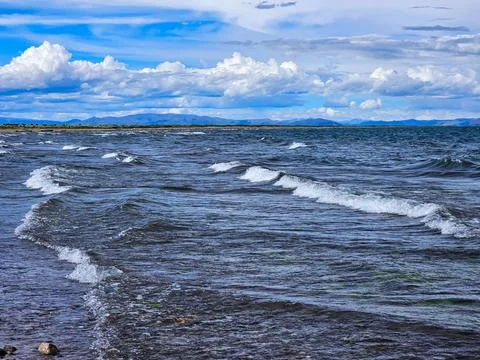 View of beach with many waves on a lake on a cloudy day Stock Photos