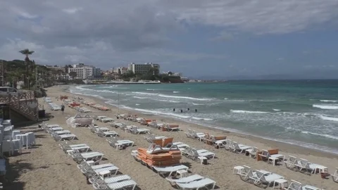 View of the beach of sand, palm trees, sun beds and sea with waves Stock Footage 69850228