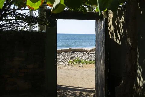 View on a beach seen from a dark space with opened door. Rocky beach Stock Photos