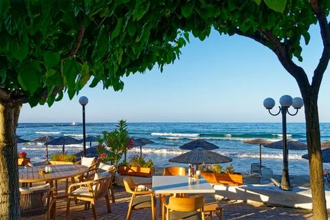 View of the beach with trees and empty tables of local restaurant Stock Photos