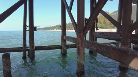View of the beach from under the old rusted pier Stock Footage 164362207