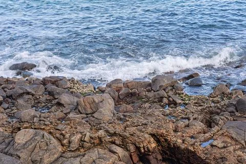 View of beach waves breaking on dark rocks during low tide. Paradise beach... Photos