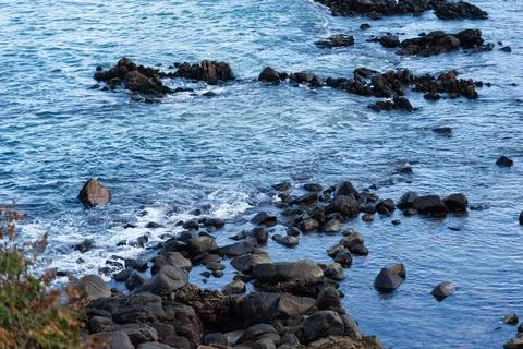 View of beach waves breaking on dark rocks during low tide. Paradise beach... Foto stock