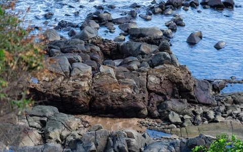 View of beach waves breaking on dark rocks during low tide. Paradise beach... Photos
