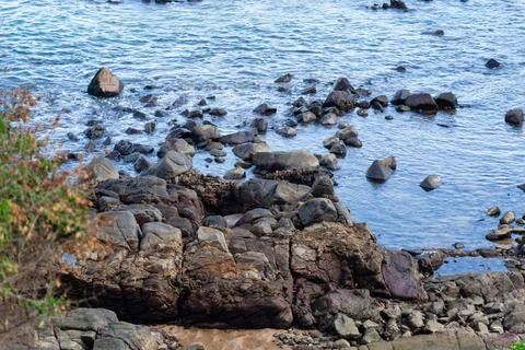 View of beach waves breaking on dark rocks during low tide. Paradise beach... Stock Photos