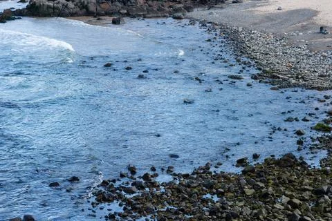 View of beach waves breaking on dark rocks during low tide. Paradise beach... Stock Photos