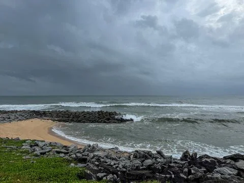 View of a beach with waves ,sand ,rocks ,greenery and blue sky. Foto stock