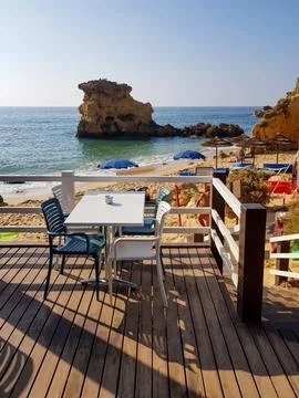 View of a beachside cafe at noon with empty tables and umbrellas nearby Stock Photos