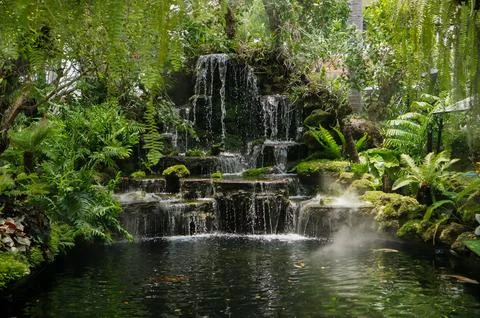 View of a beautiful artificial waterfall surrounded by lush green tropical .. Foto stock