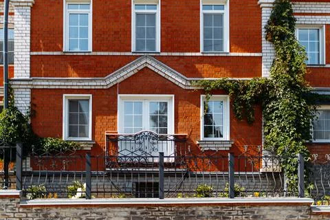 View of the beautiful facade of a red brick house with a vintage balcony and Stock Photos