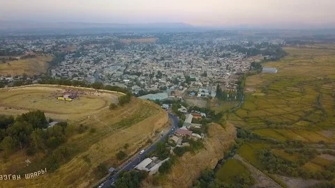 View of beautiful mountains, stadium with crowd, houses and trees with a drone Stock Footage 84961757