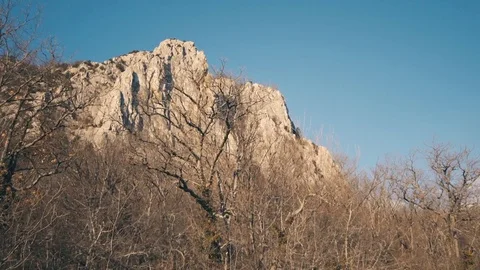 View of a beautiful Rock mountain cliff through a winter forest without foliage Video stock 85132487