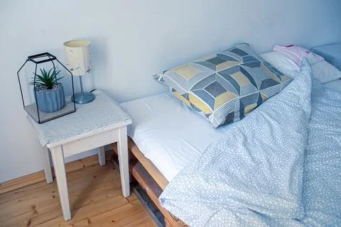 View of the bed and bedside table in the morning.Detail of pillow and blanket Stock Photos