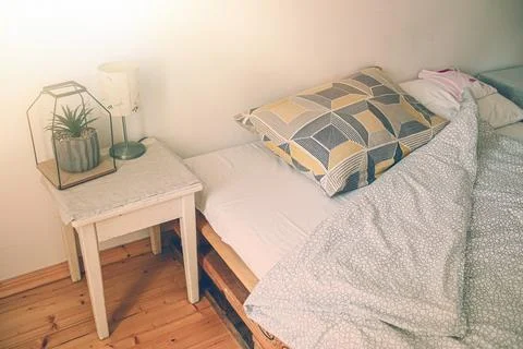 View of the bed and bedside table in the morning.Detail of pillow and blanket Stock-Fotos