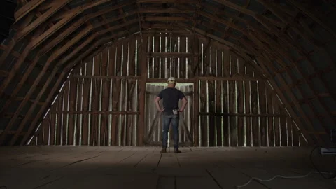 View From Behind of Blue Collar Working Man with Hands on Hips in empty barn Video stock 219559394