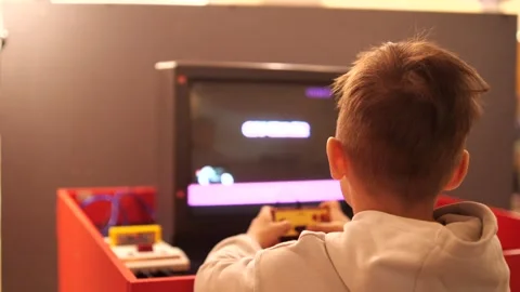 View from behind boy plays old vintage eight-bit 8 bit video console Stock Footage 270155847