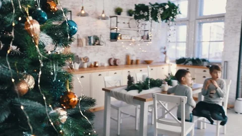 View from behind the Christmas tree to children in kitchen Stock Footage 120877951