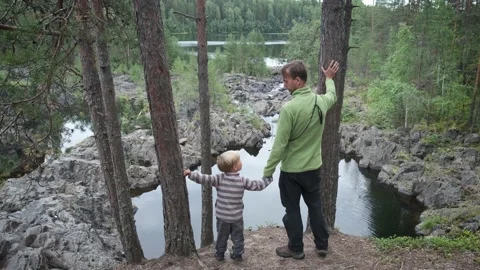 View from behind father and son hikers standing on cliff near mountain river. Stock Footage 140363901
