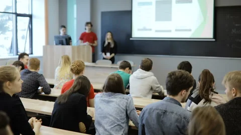 View from behind of a group of students in a classroom, listening as their Stock Footage 85467831