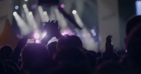 View from behind of hands hold smartphone among people at rave party with light 動画素材 68647652