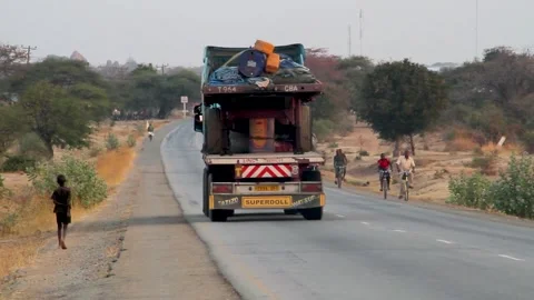 A view from behind of a heavy-duty cargo truck traveling along a paved road in Stock Footage 345410039