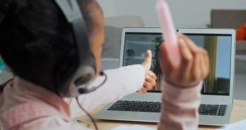 View from behind little active afro american schoolgirl in headphones talking Stock Footage 148313338