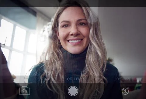 View From Behind Mobile Phone Screen As Woman Takes Selfie At Home Stock Photos