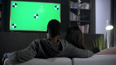 View from behind of relaxed young couple cuddled up on a comfy sofa watching TV Stock Footage 100204335